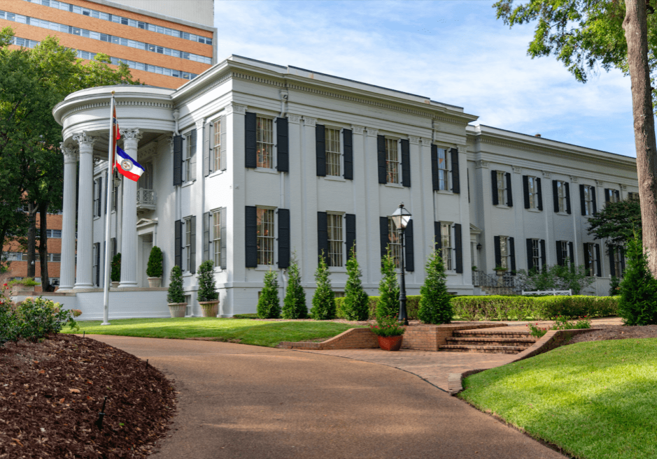 A large white building with trees in front of it.